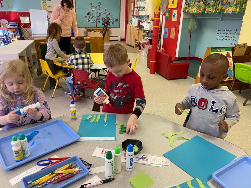 Children doing crafts at a table in a classroom
