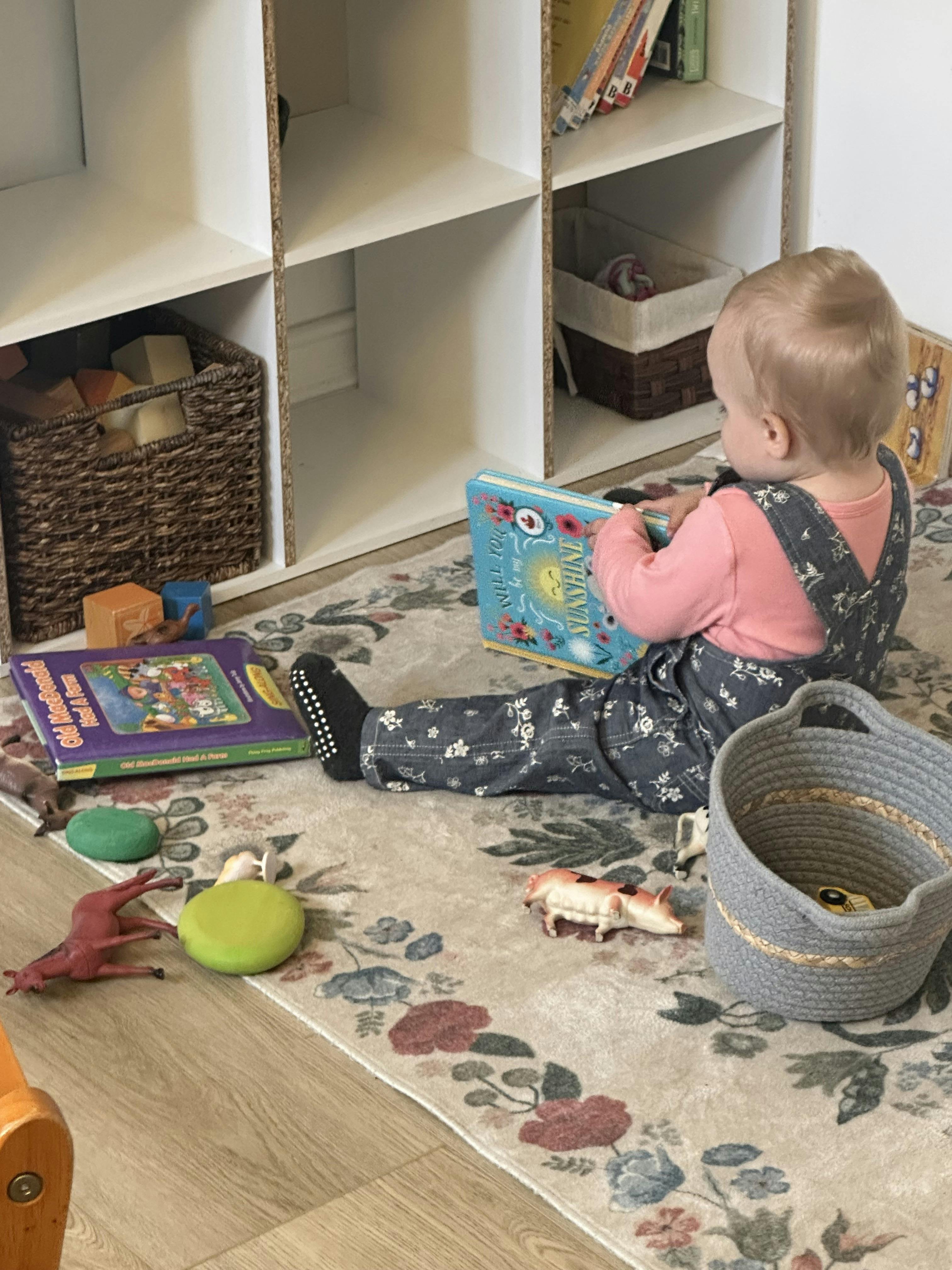 child in a classroom sitting on the floor reading a book