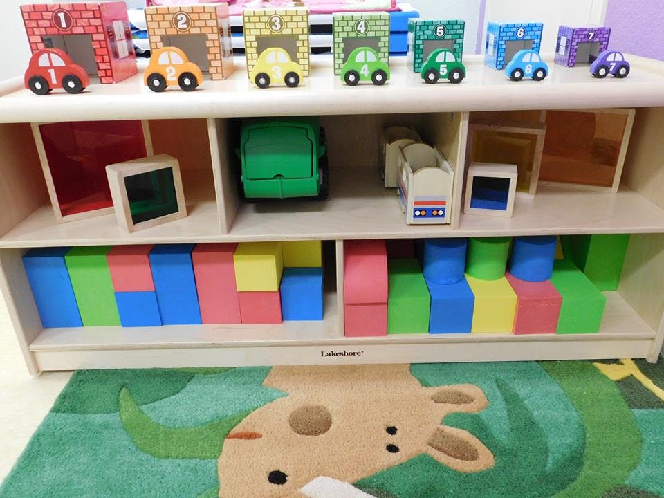 Wooden shelf with toy cars, blocks, and other toys