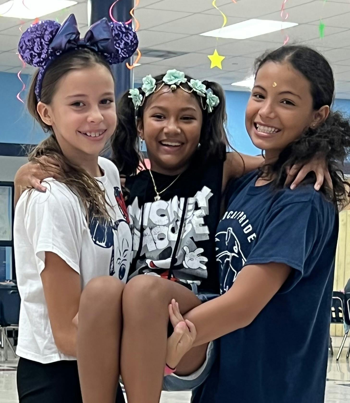 Three children smiling, two holding up a third child