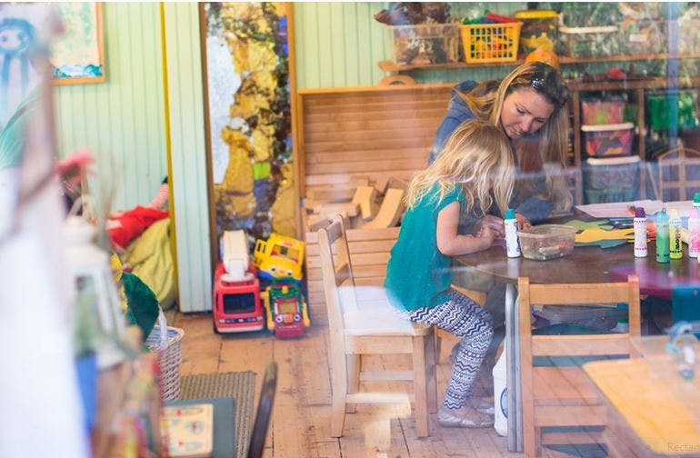 Person helping a child at a table