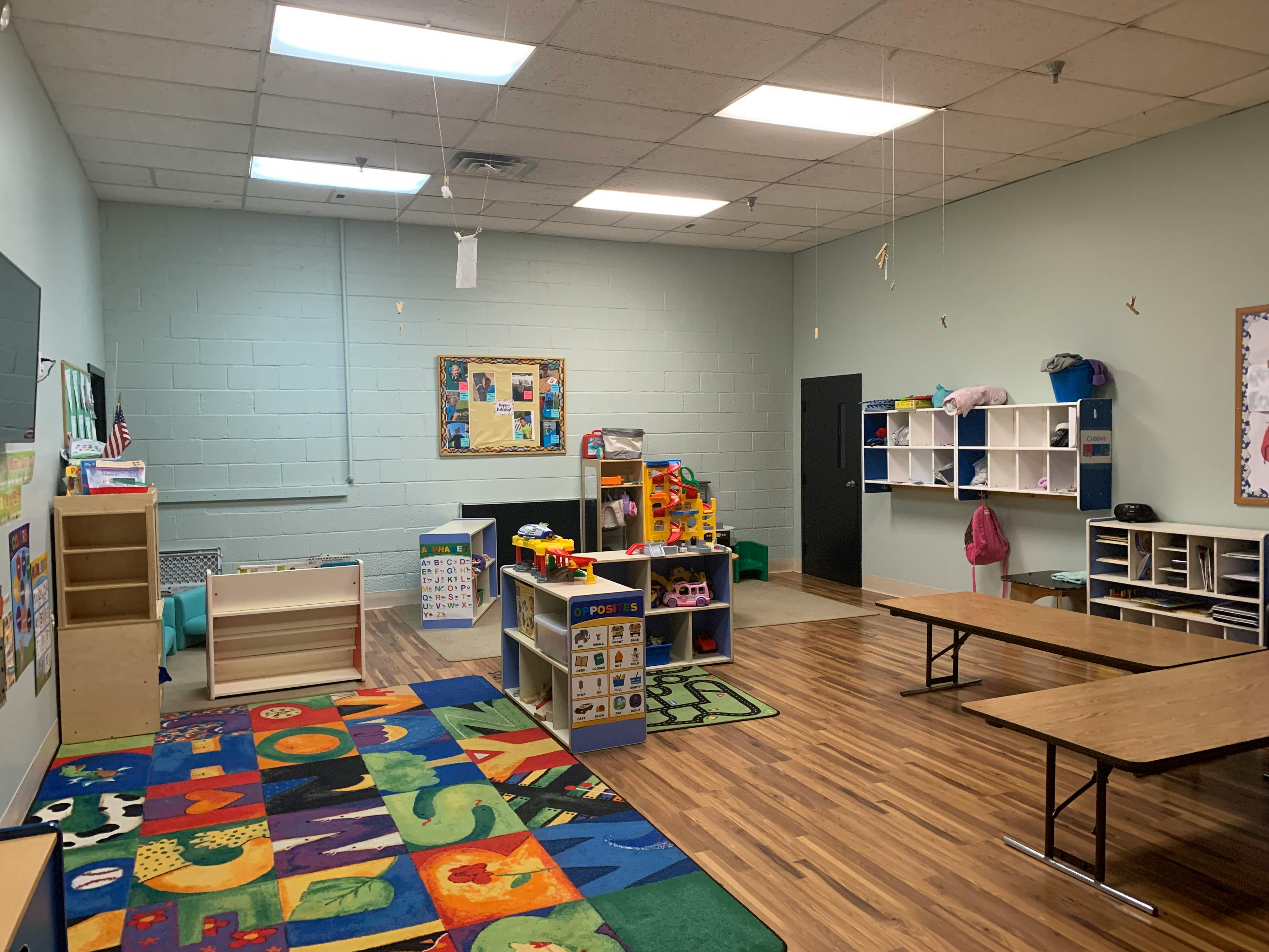 Classroom with colorful alphabet rug, shelves, and tables