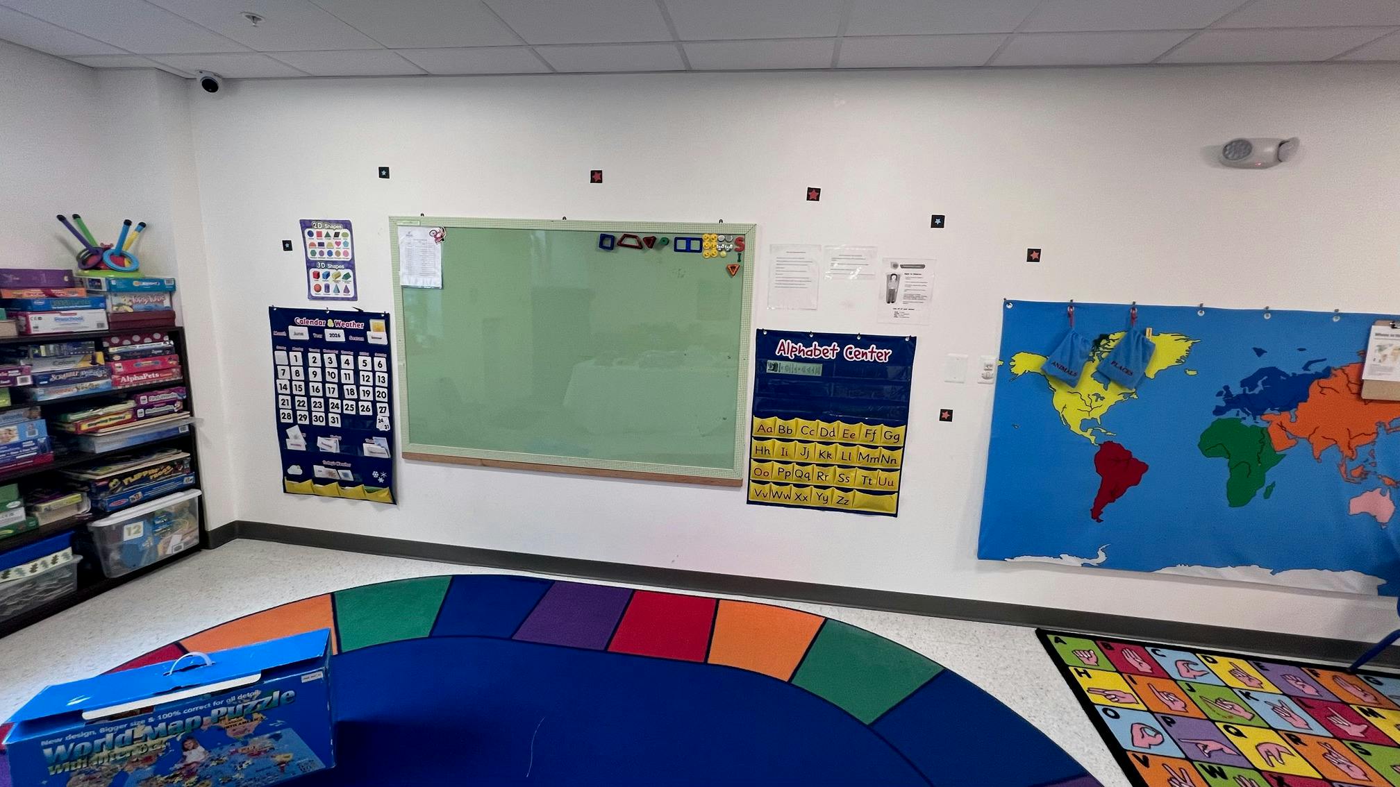 Classroom wall with educational charts, a whiteboard, and a map