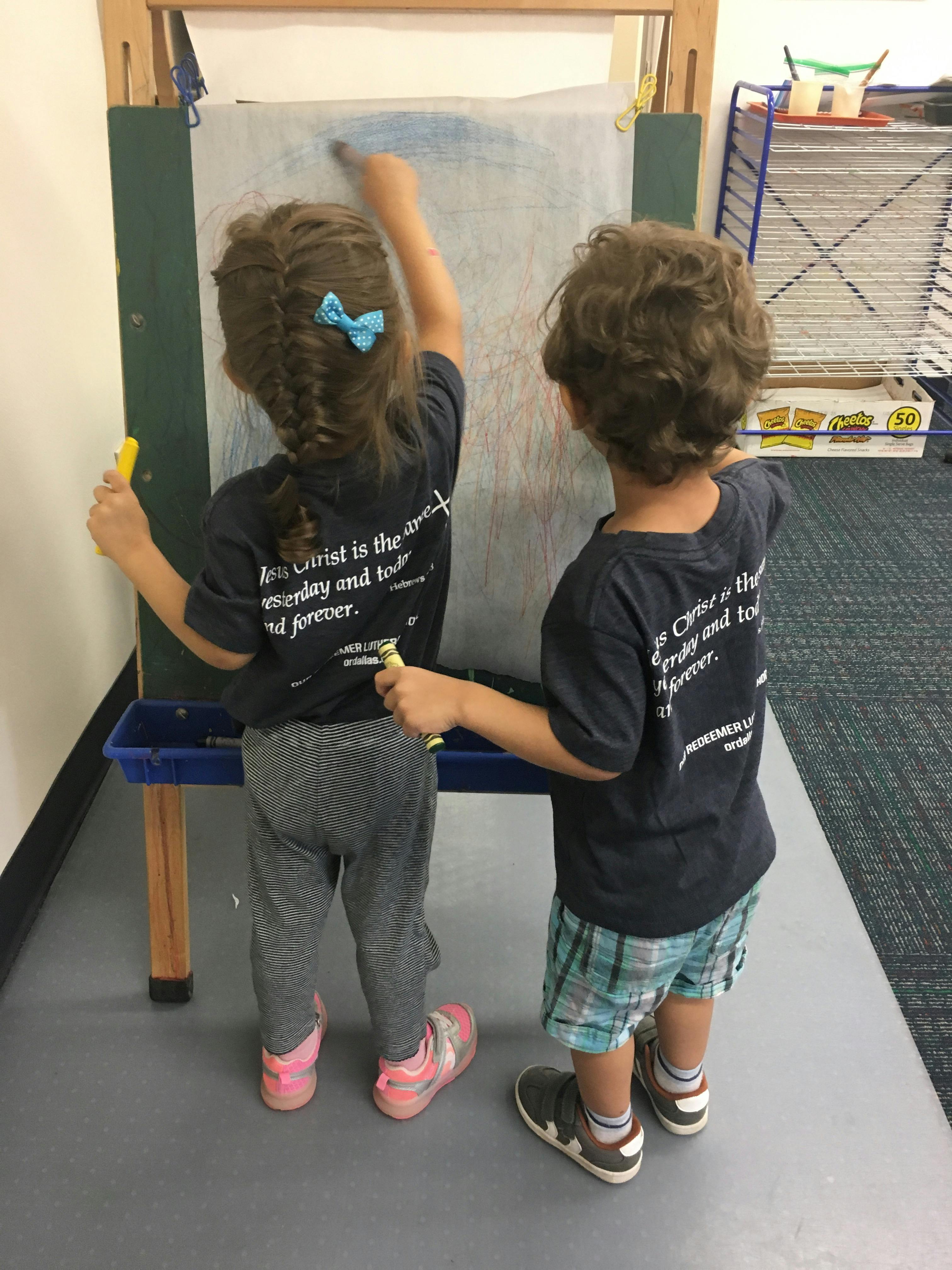 Two children drawing on an easel