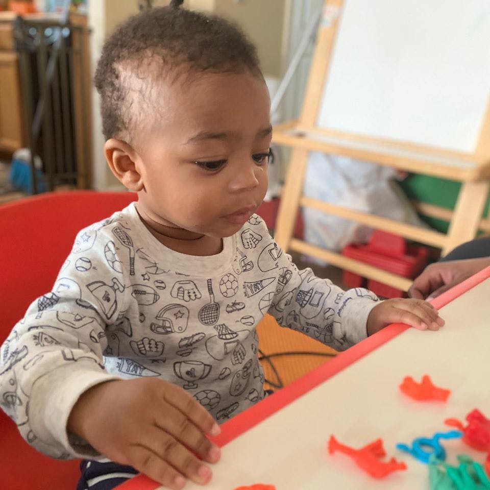Child playing with small colorful objects on a table