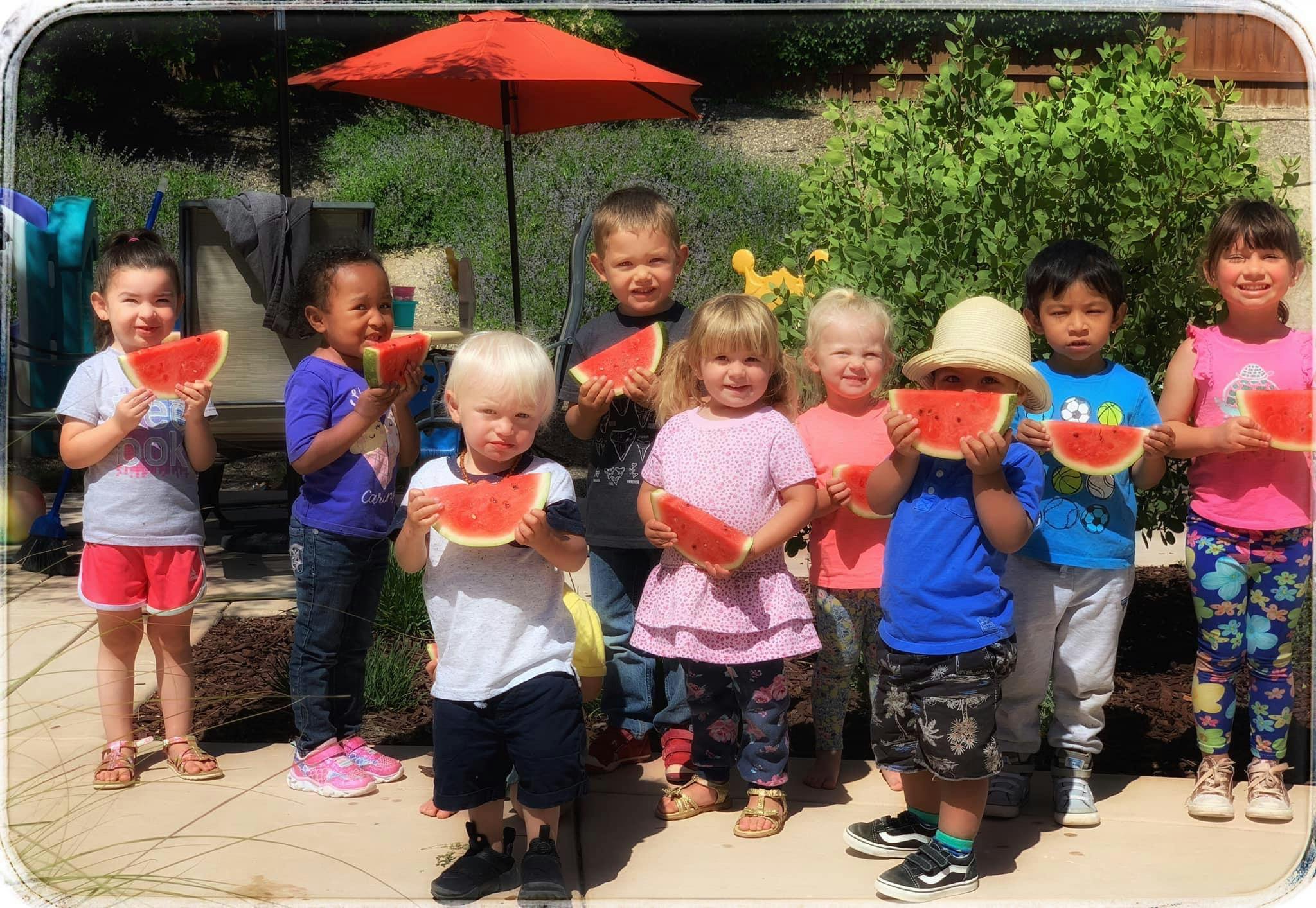 Group of children holding slices of watermelon outdoors