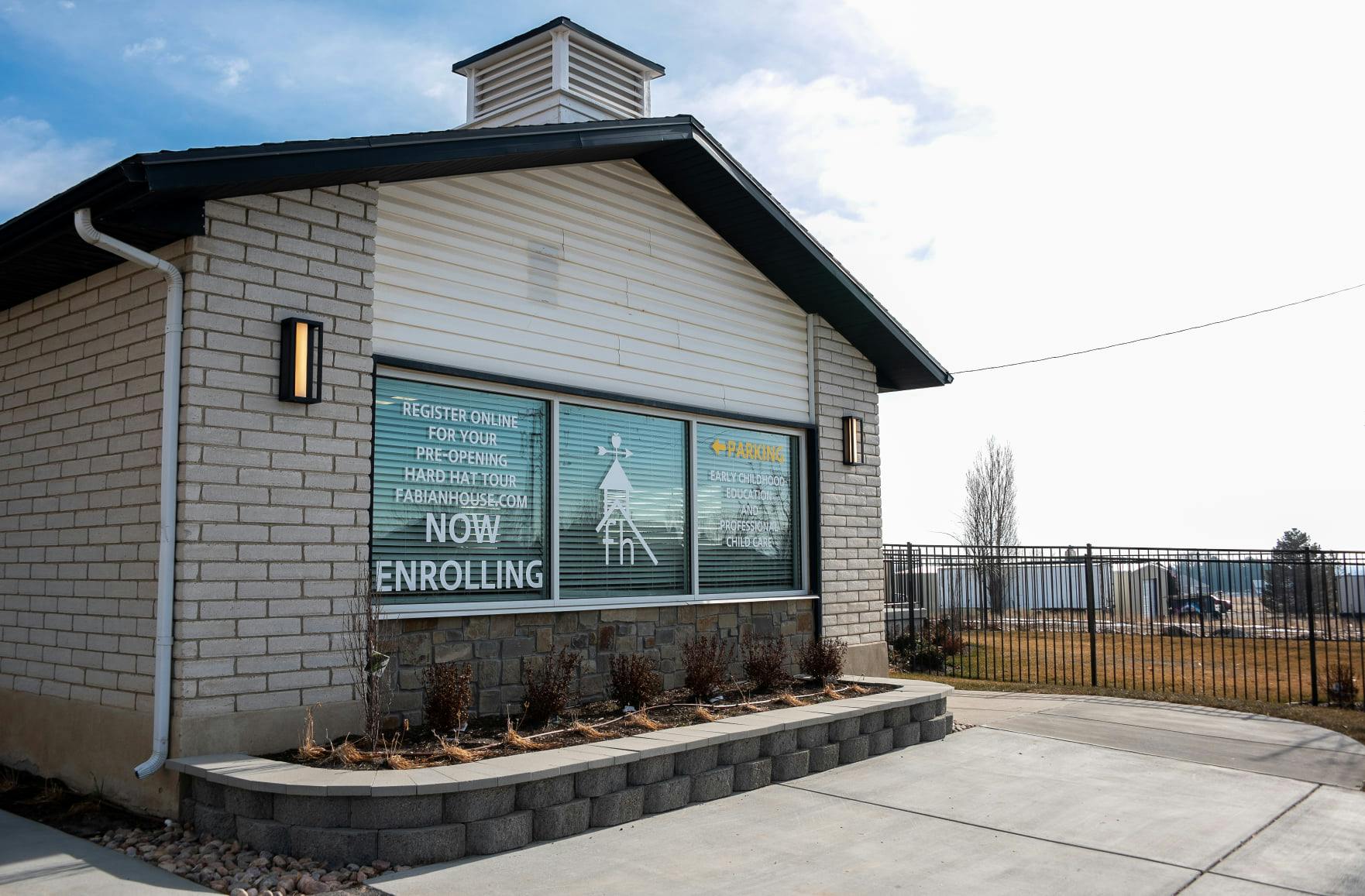 Building with "NOW ENROLLING" sign in window