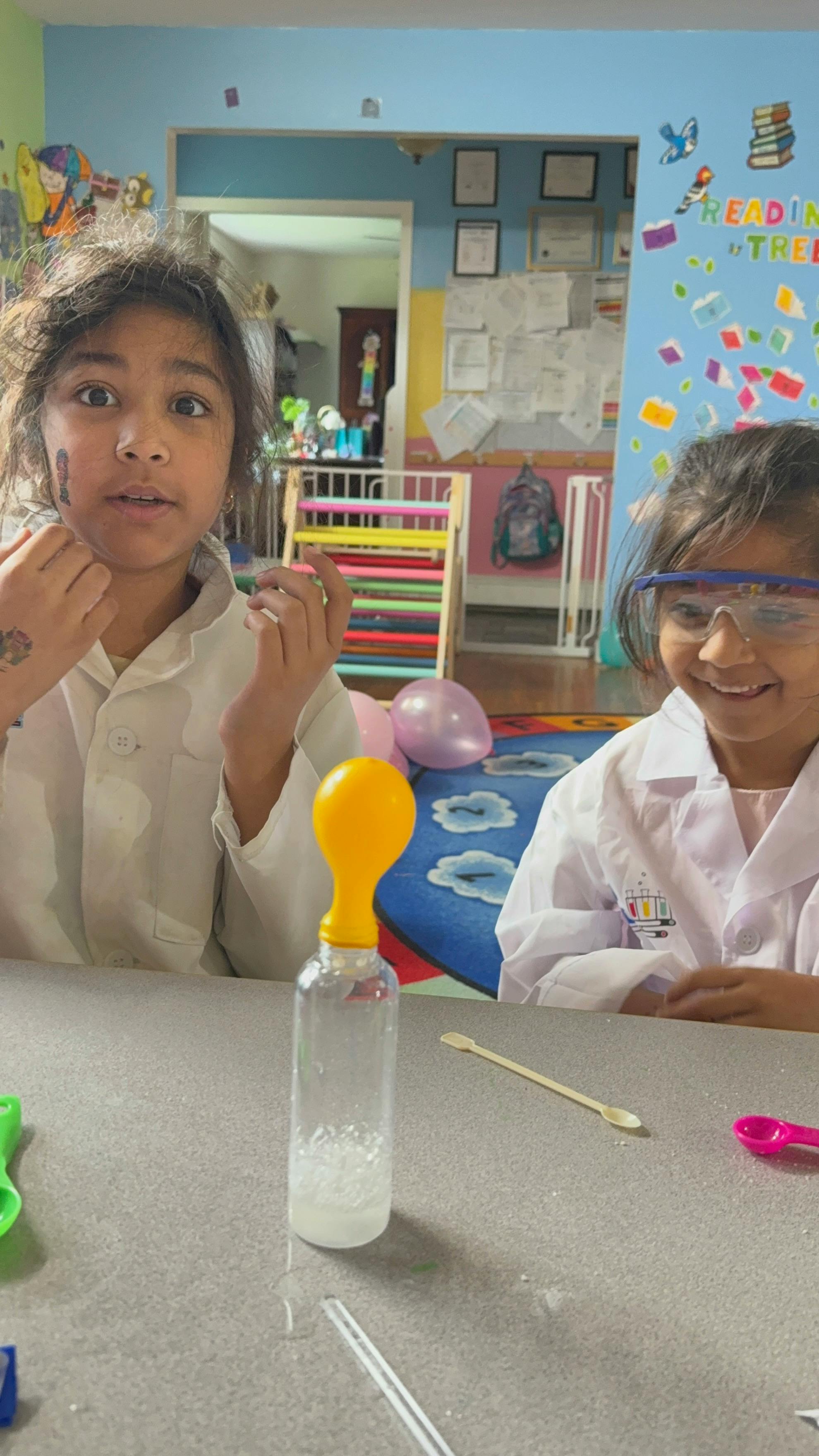 Two children in lab coats conducting a science experiment with a balloon