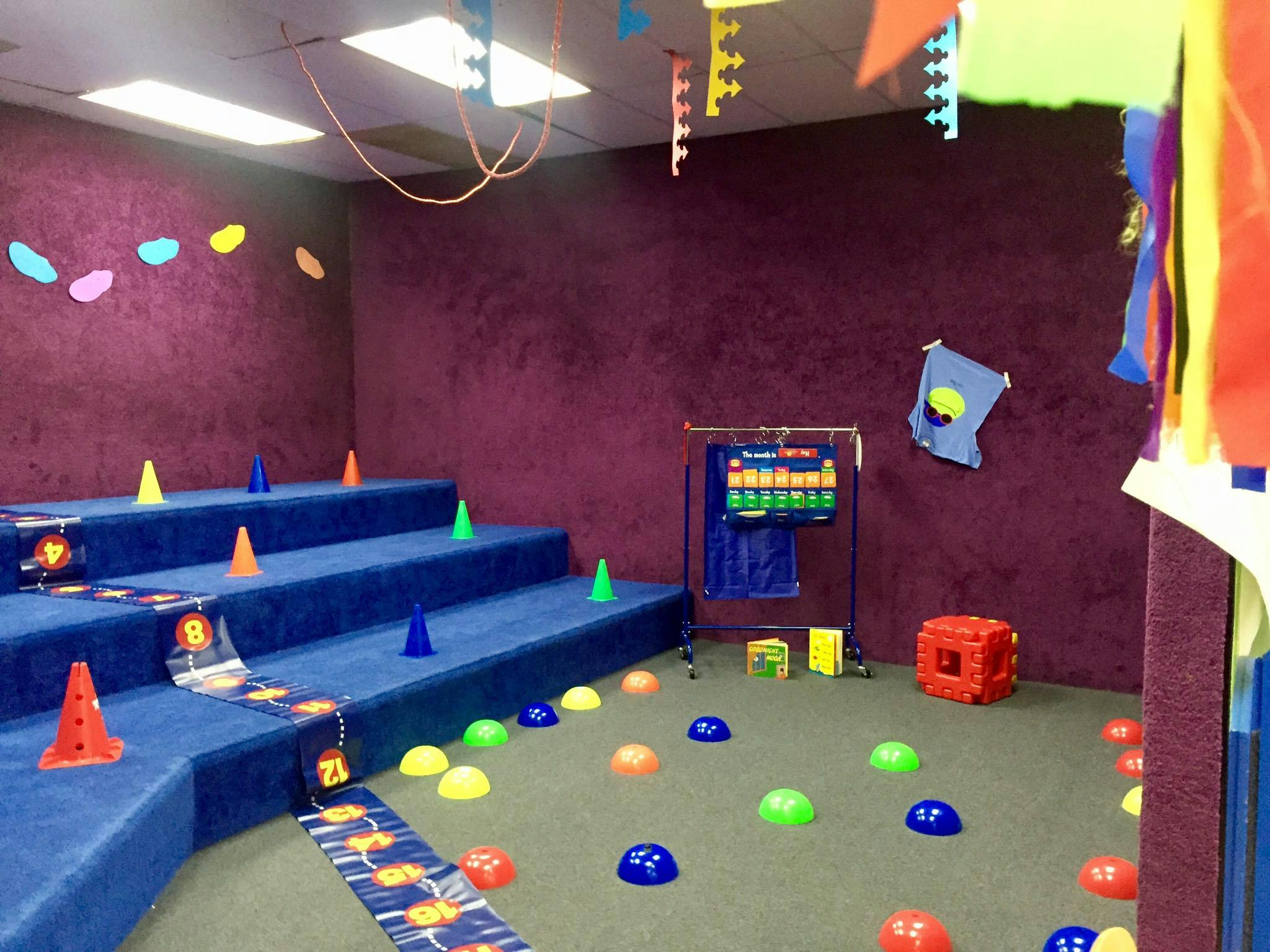 Indoor play area with blue steps, colorful cones, and floor markers
