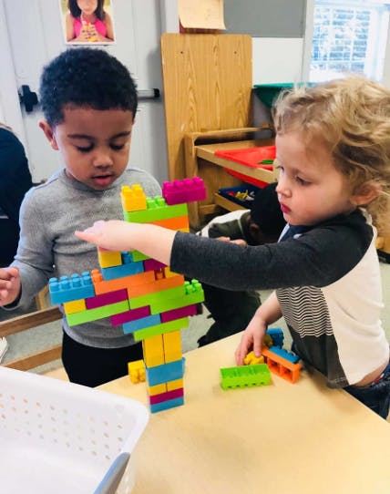 Two children playing with colorful building blocks on a table