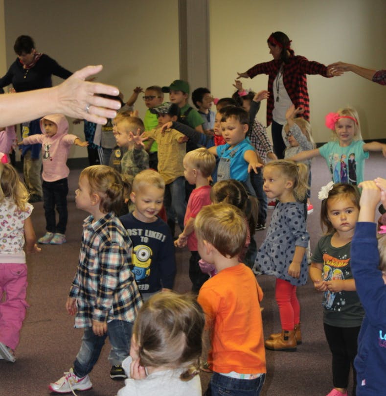 Adults and children standing in a group with arms outstretched