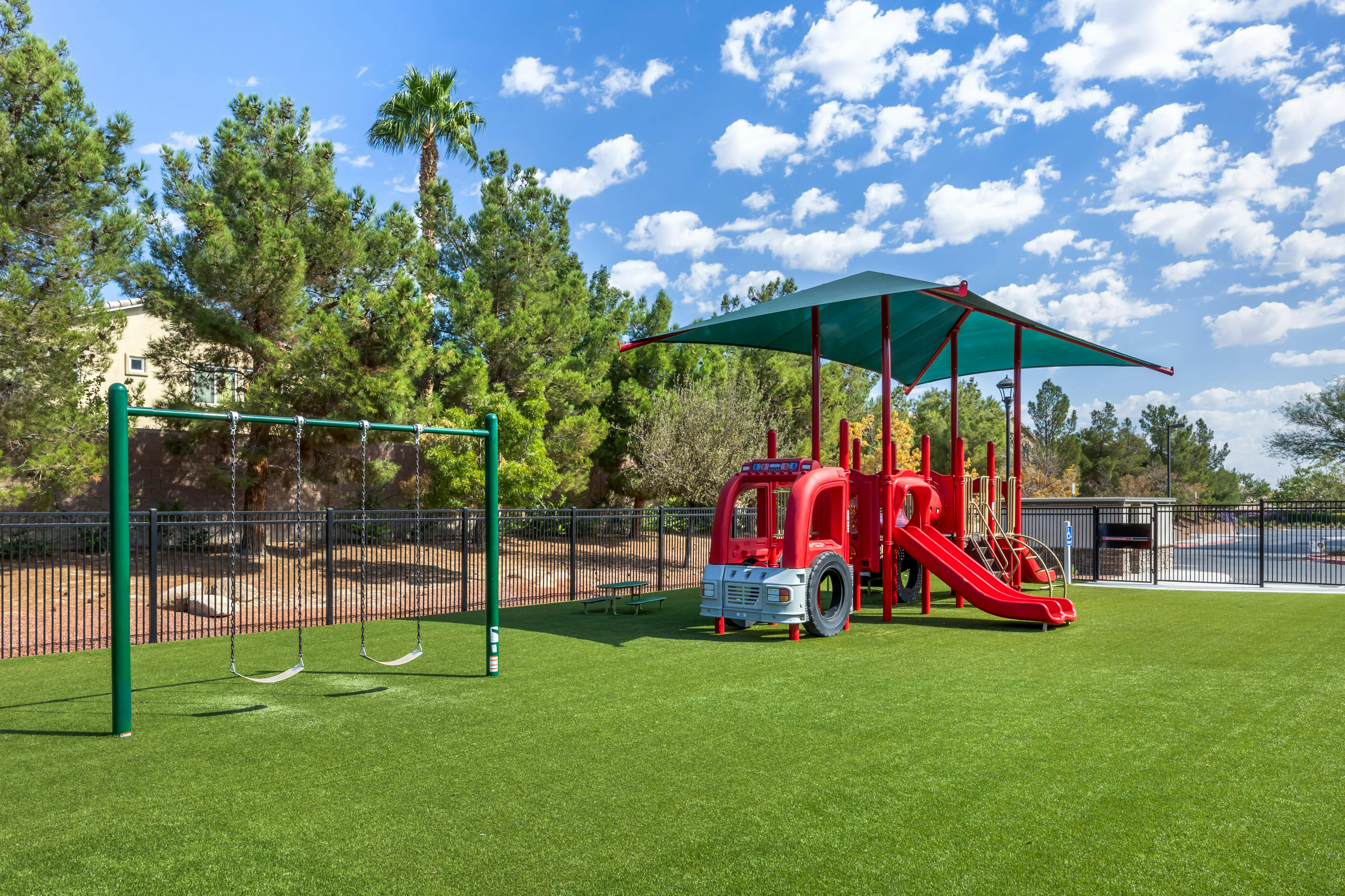 Playground with swings and a red fire truck shaped play structure