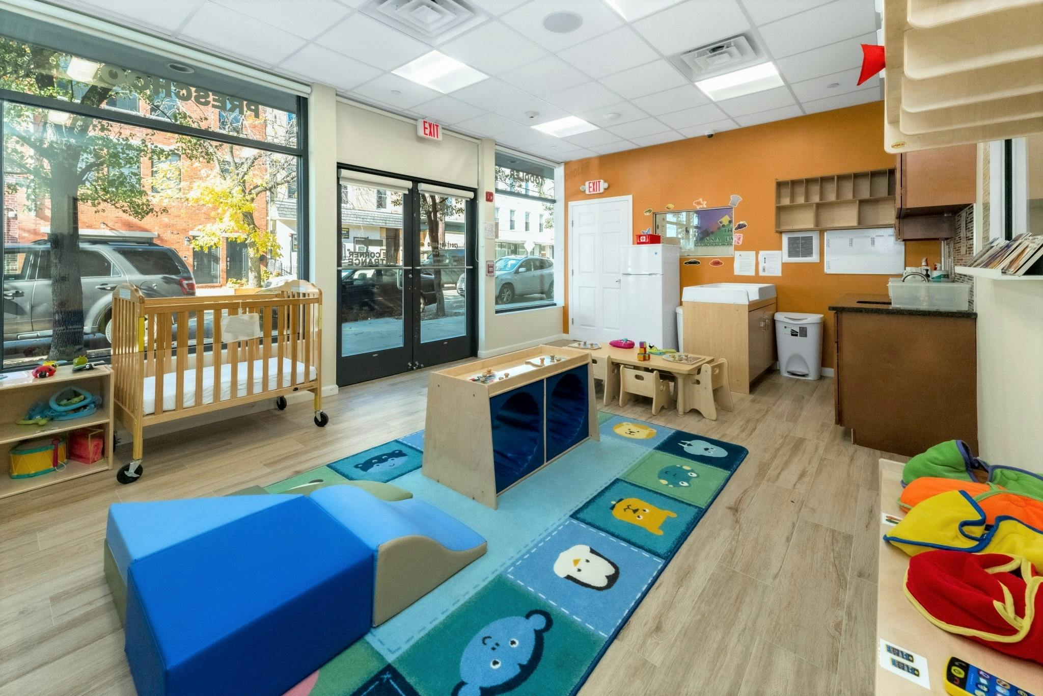 Playroom with a crib, soft play equipment, and a colorful rug