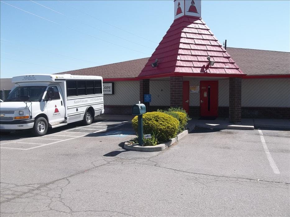 White shuttle bus parked outside a building with a red roof