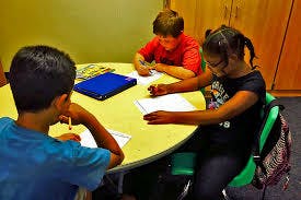 Three children writing at a table