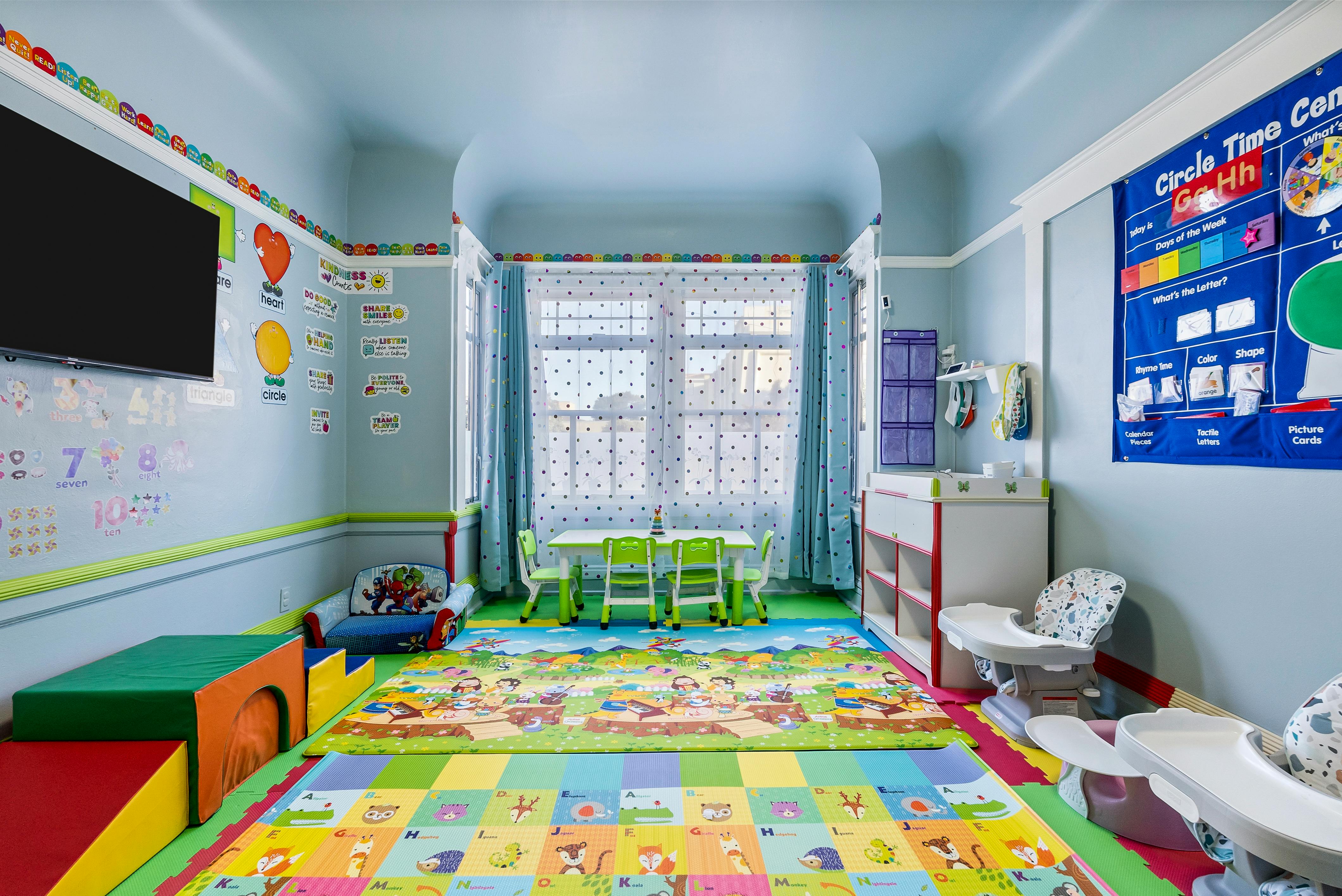 Playroom with colorful floor mats, small table and chairs, and wall decorations