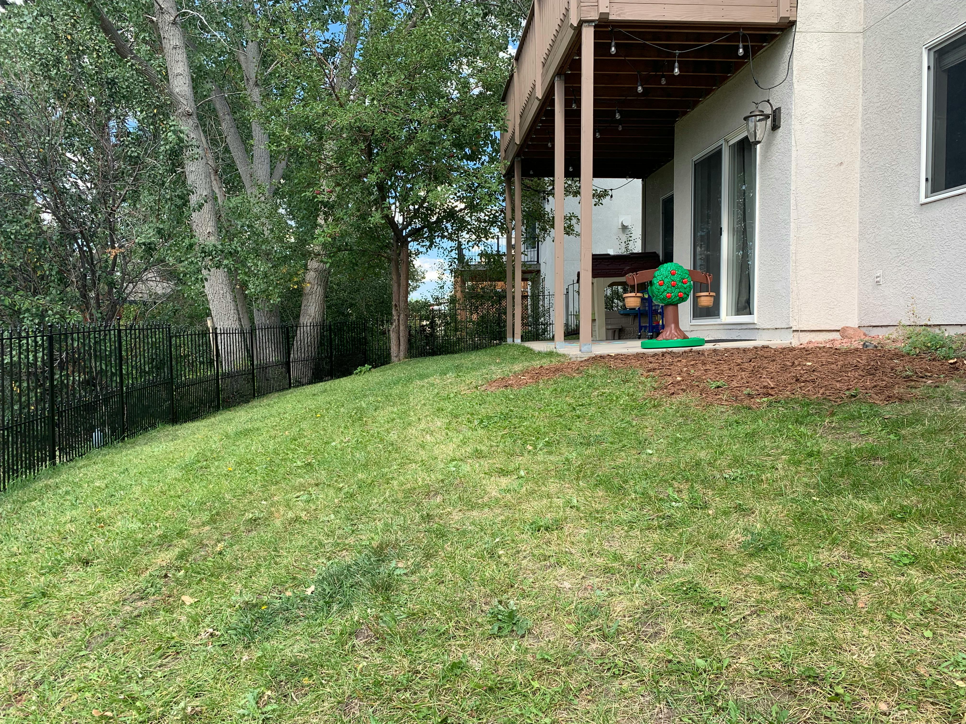 Grassy hillside next to a house with a deck