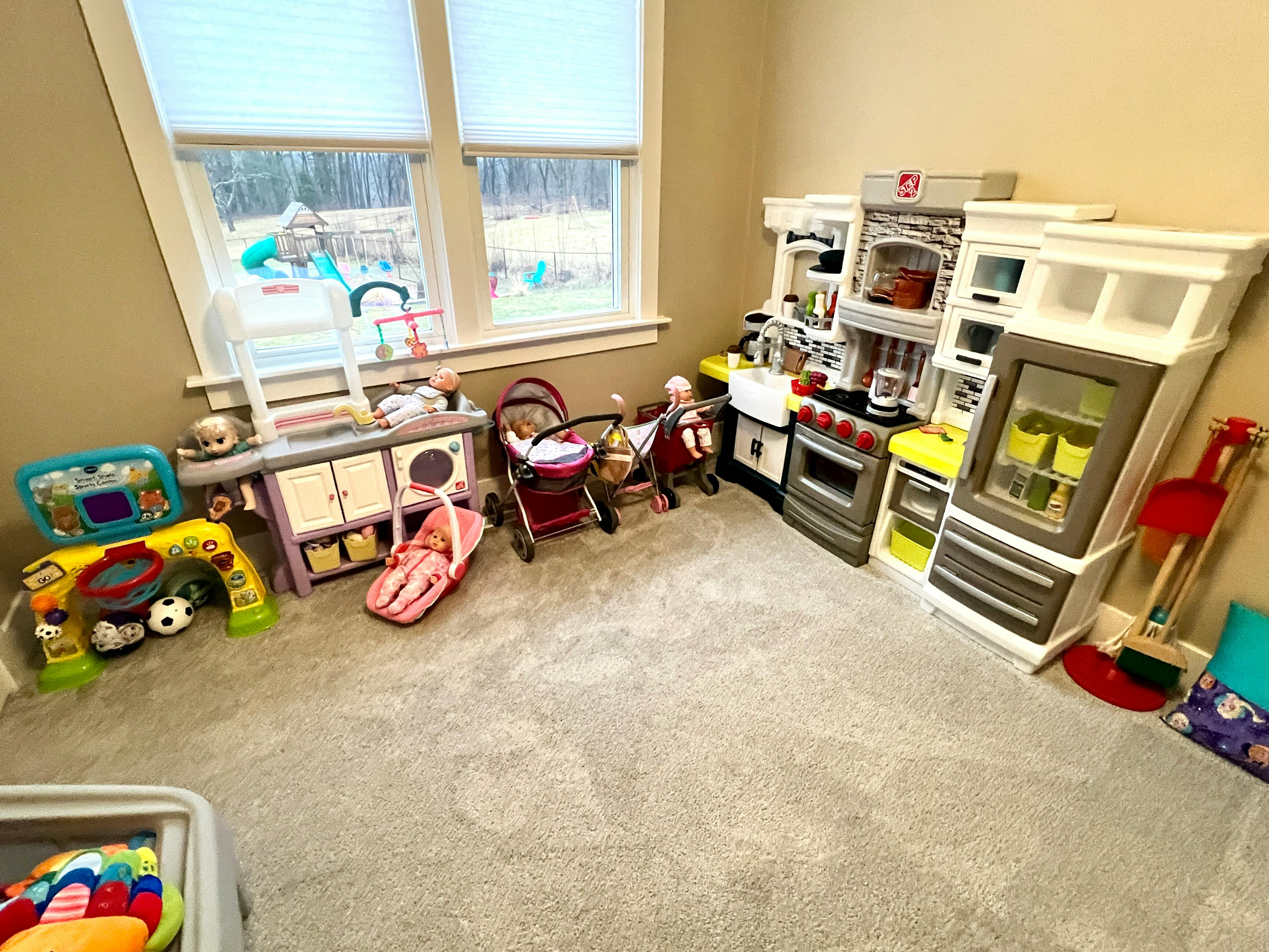 Children's play kitchen and other toys in a room with windows