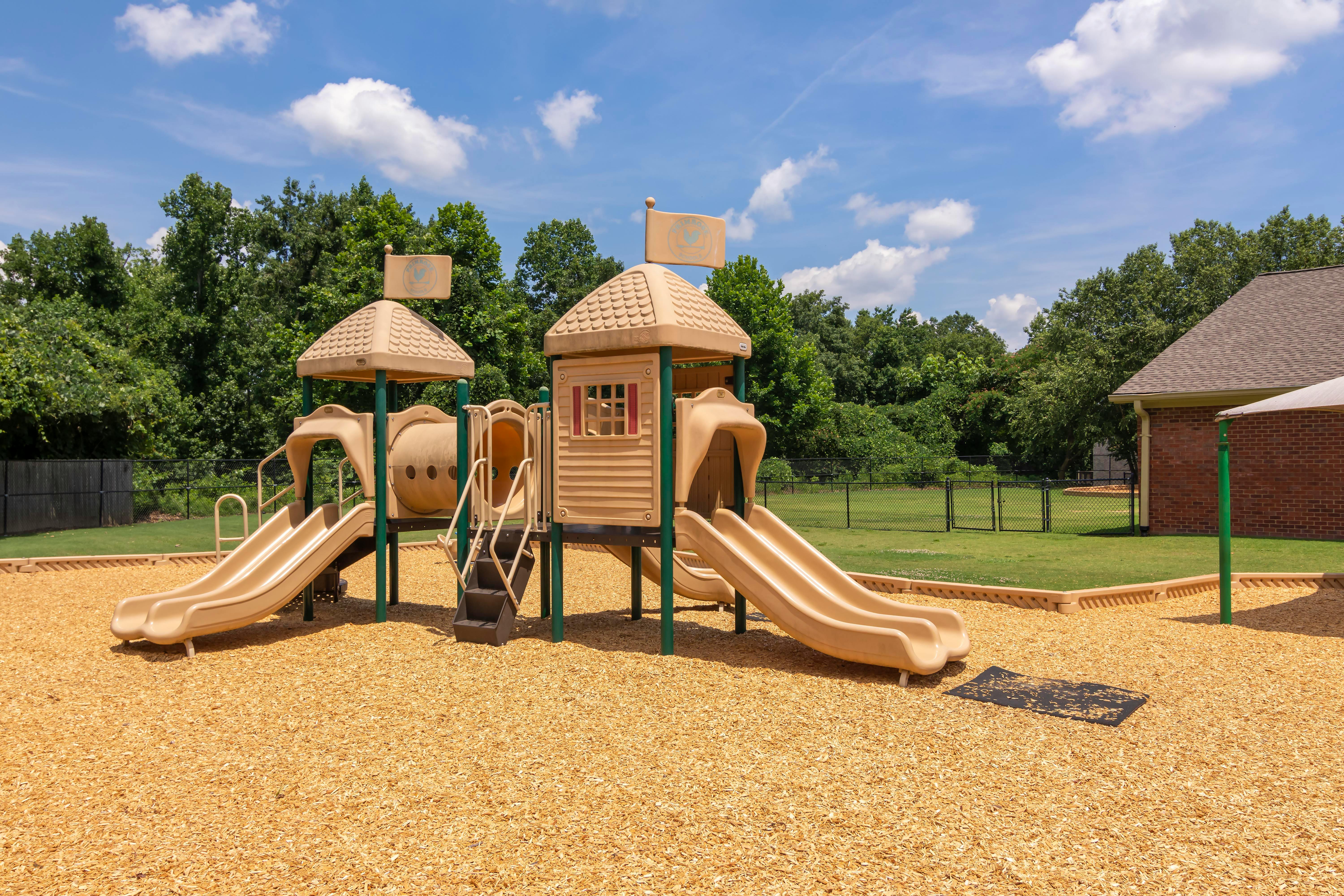 Empty children's playground with slides, stairs, and wood chip ground cover