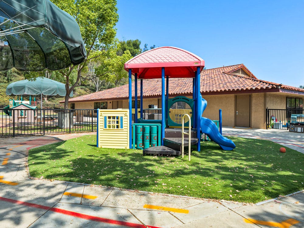 Playground with climbing structure and slide in front of a building