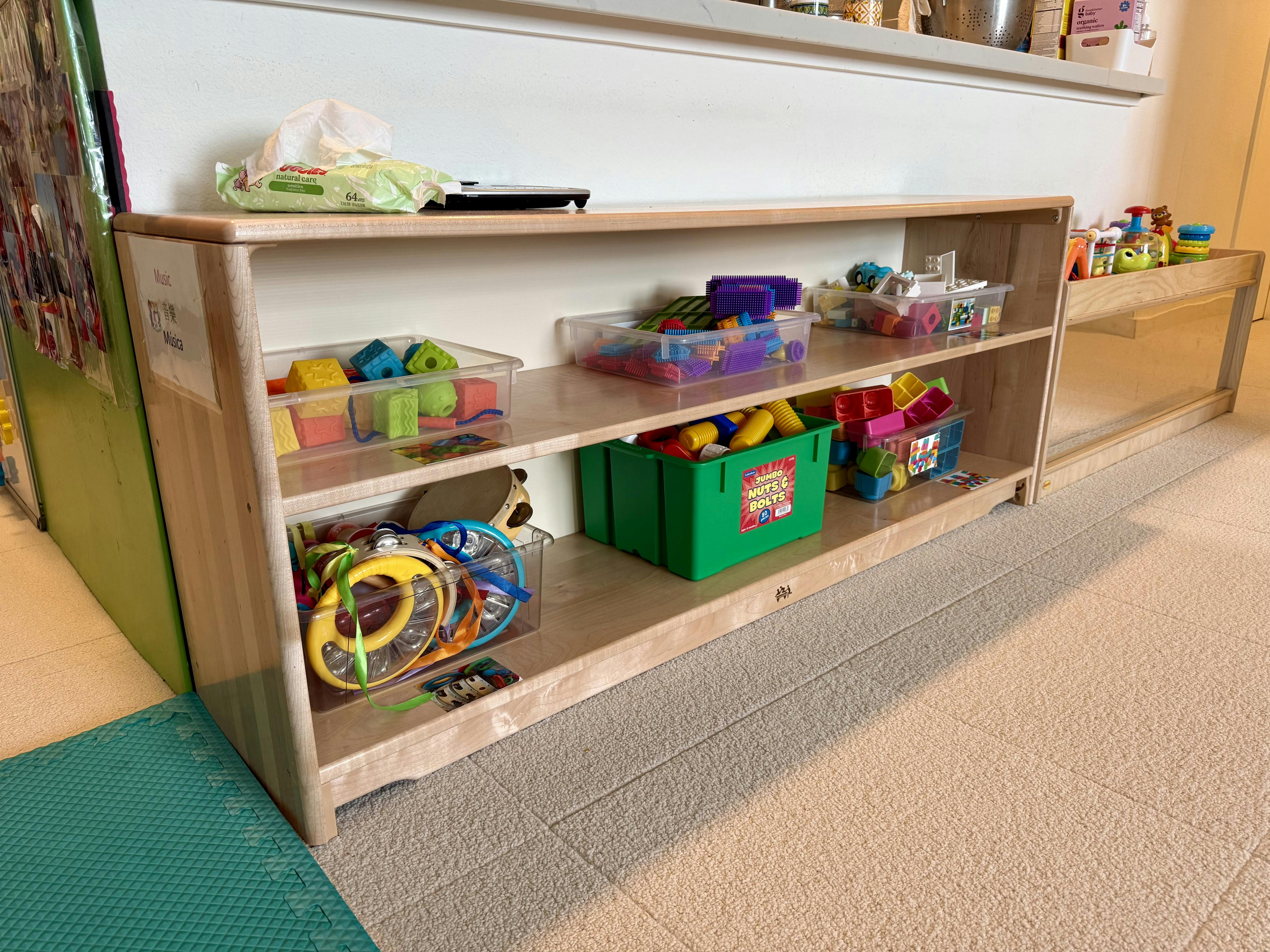 Wooden toy shelf with bins of children's toys in a classroom