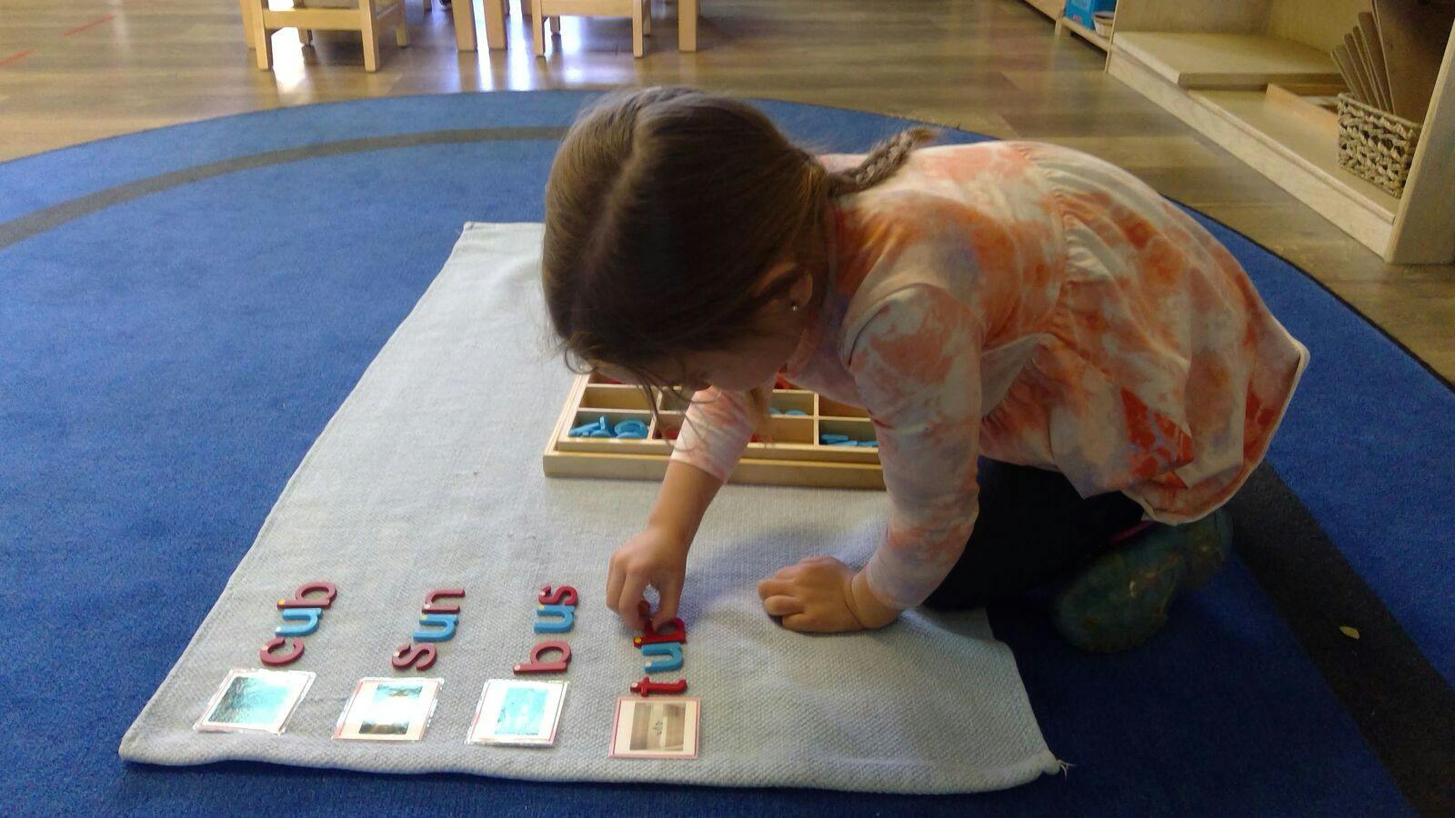 Child arranging alphabet letters on a mat to form words