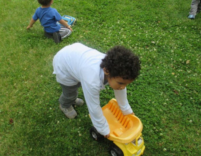 Child playing with a toy truck on grass