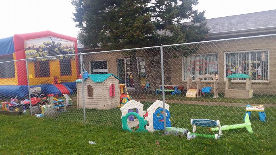Inflatable bounce house and plastic playhouses in a fenced yard