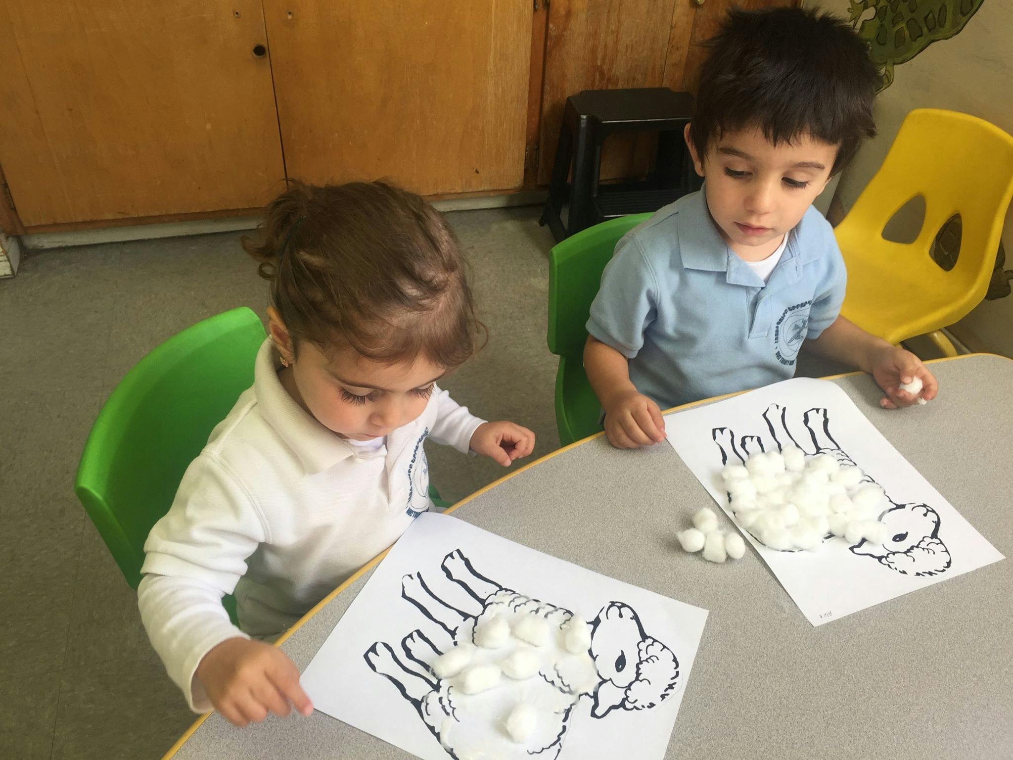Two children doing an art activity with cotton balls and drawings