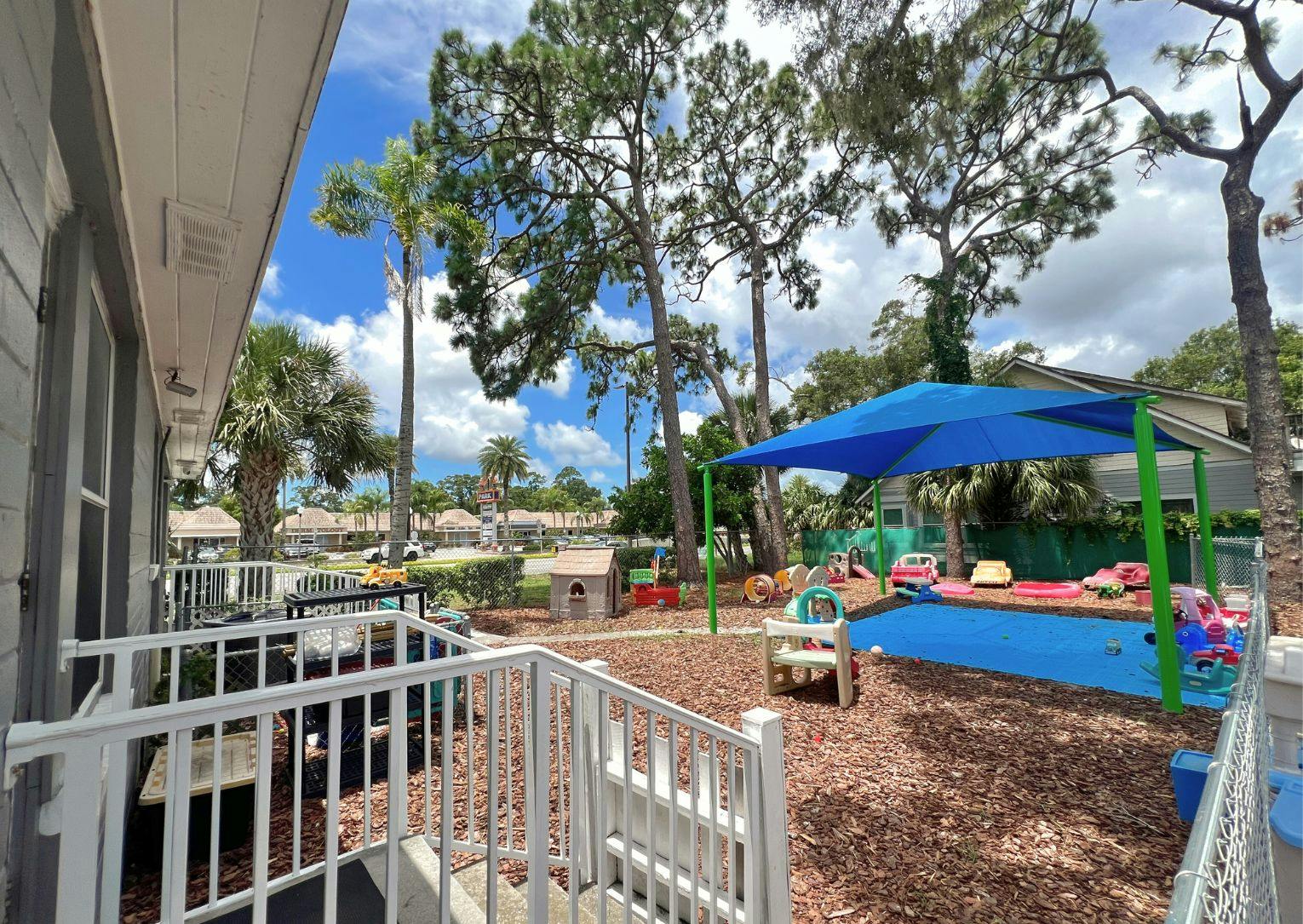 Outdoor play area with a blue shade structure and wood chip ground