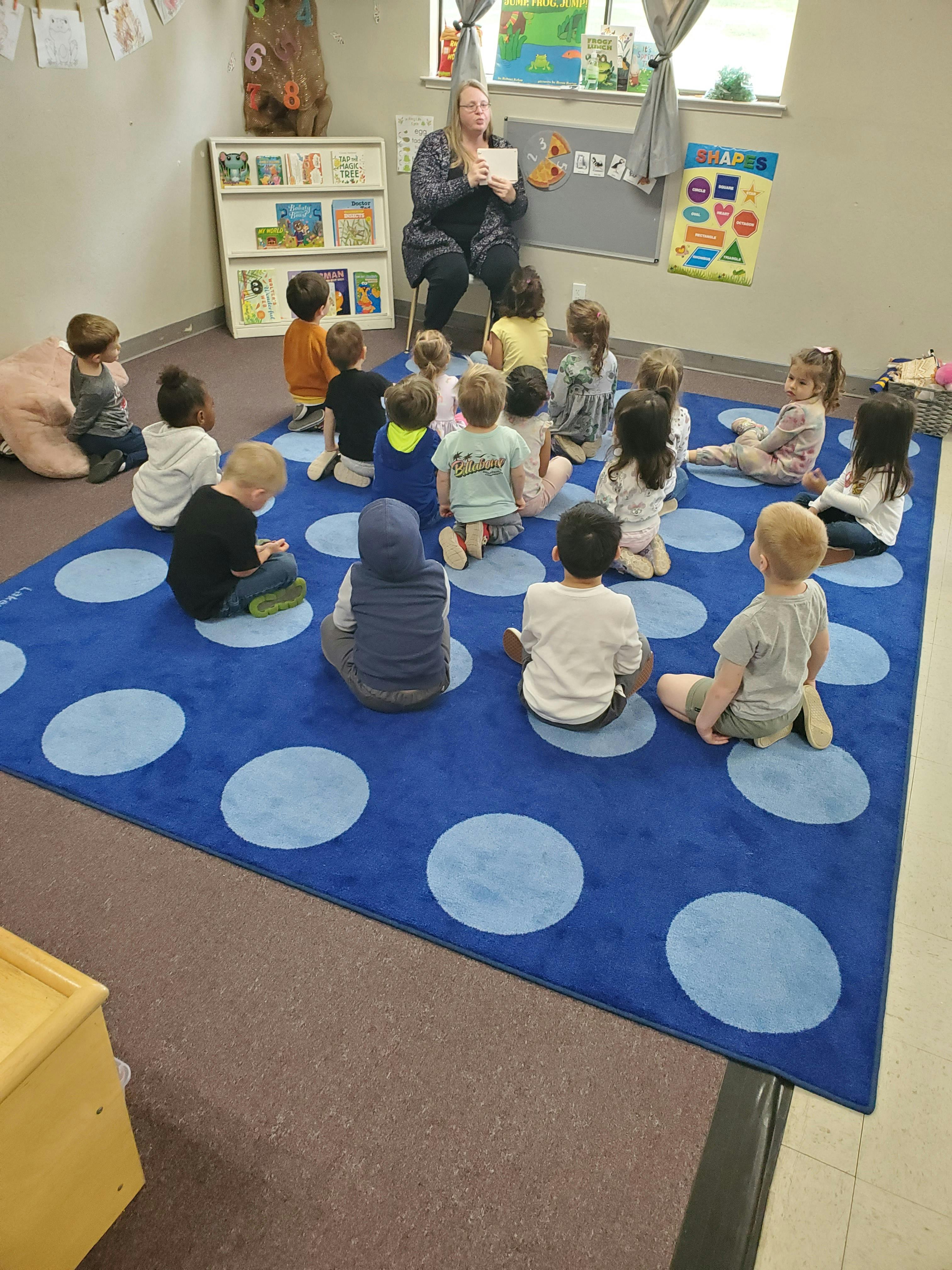 Adult reading to a group of children in a classroom