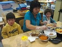 Adult and two children at a table with food