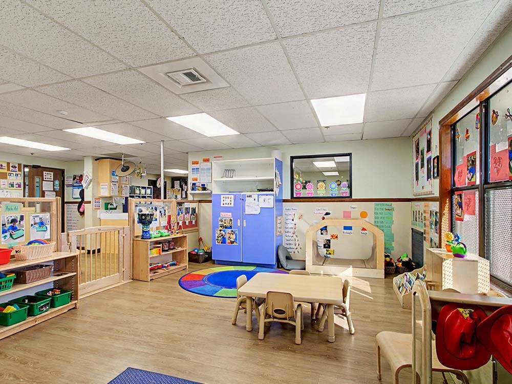 Empty colorful preschool classroom with small tables and chairs