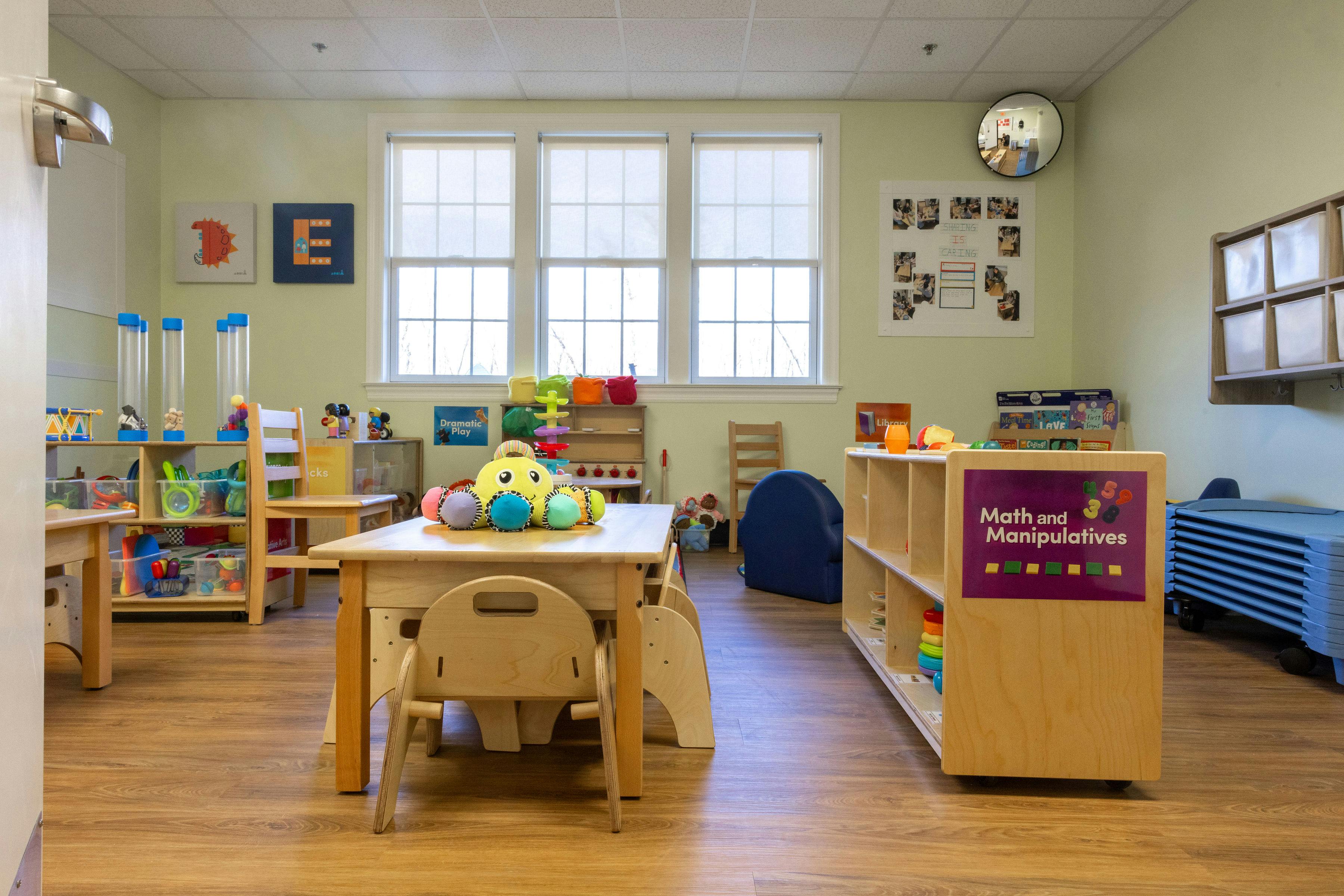 Classroom with child-sized tables and chairs, shelves with toys and books