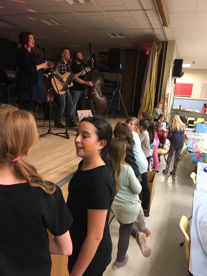 People performing music on a stage with children watching
