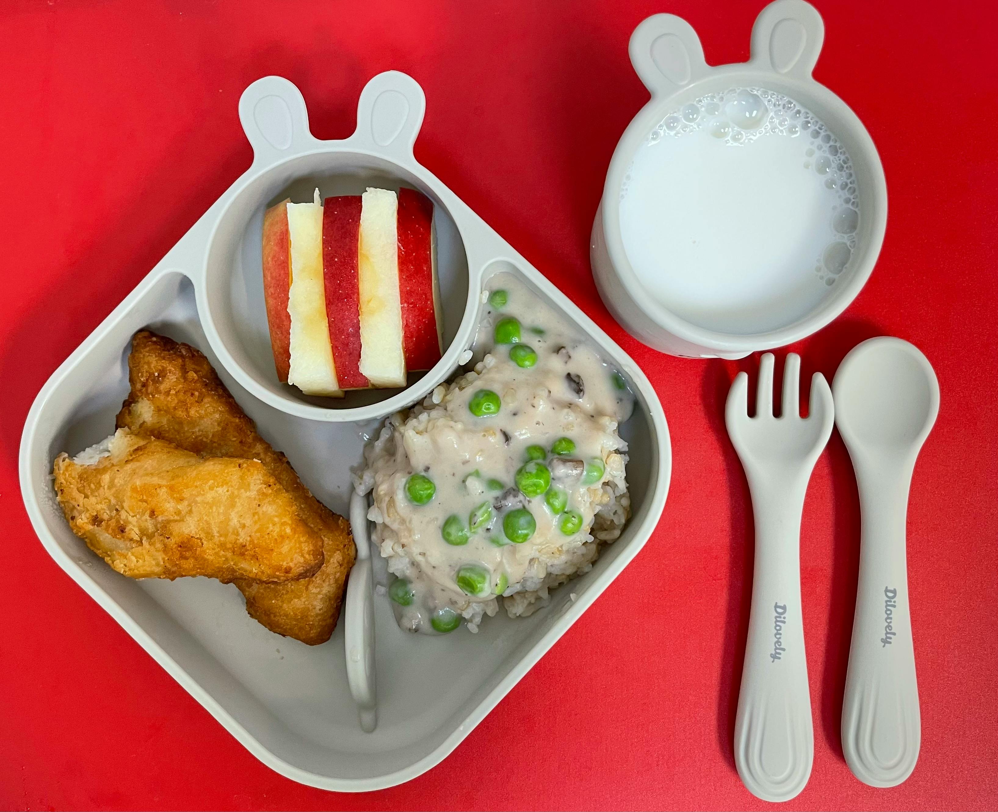 Child's plate with fish, mashed potatoes with peas, apple slices, and milk