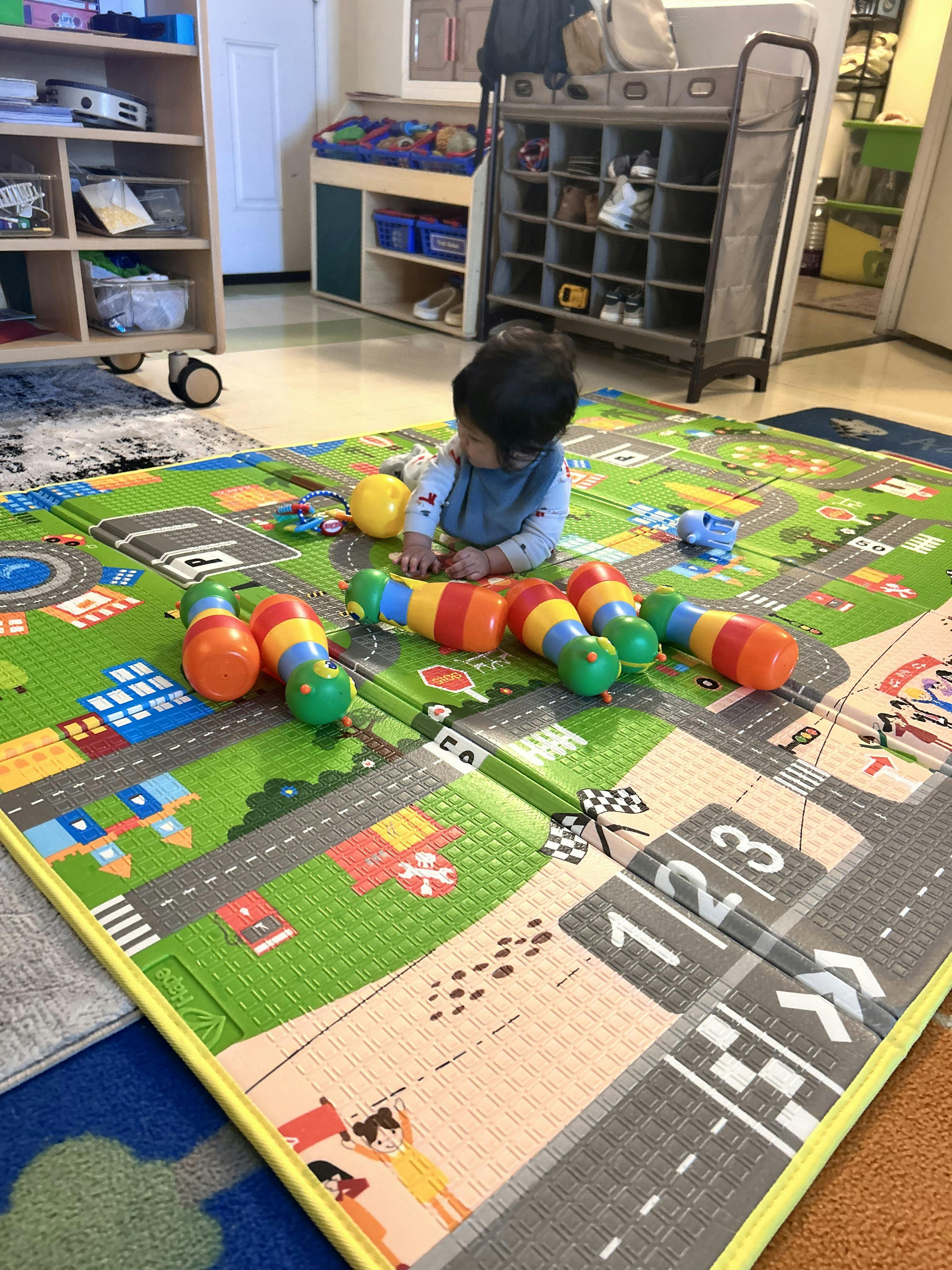 Child playing with colorful bowling pins on a play mat