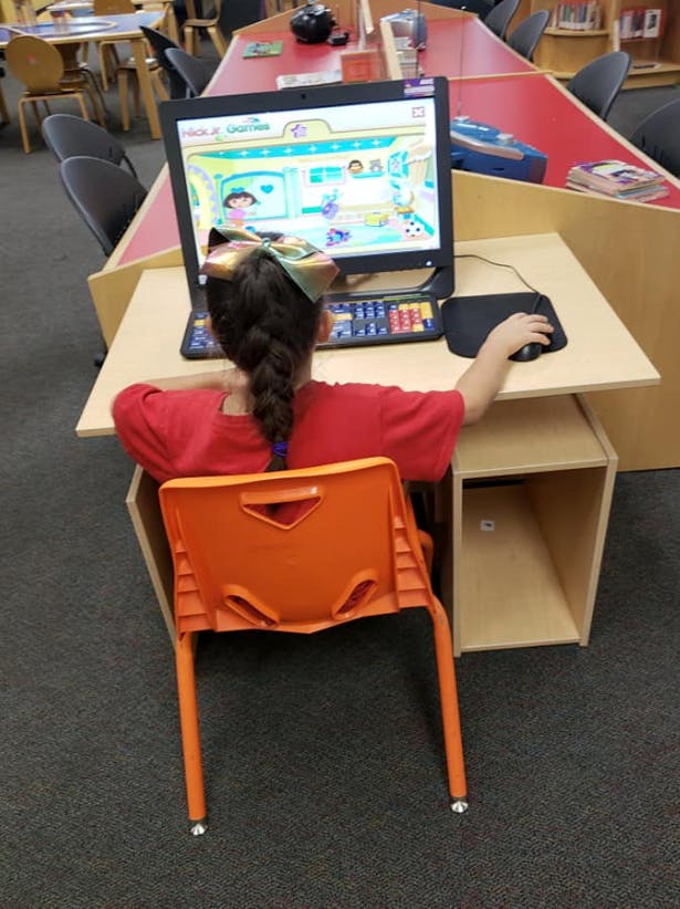 Child with braided hair using a computer mouse at a desk
