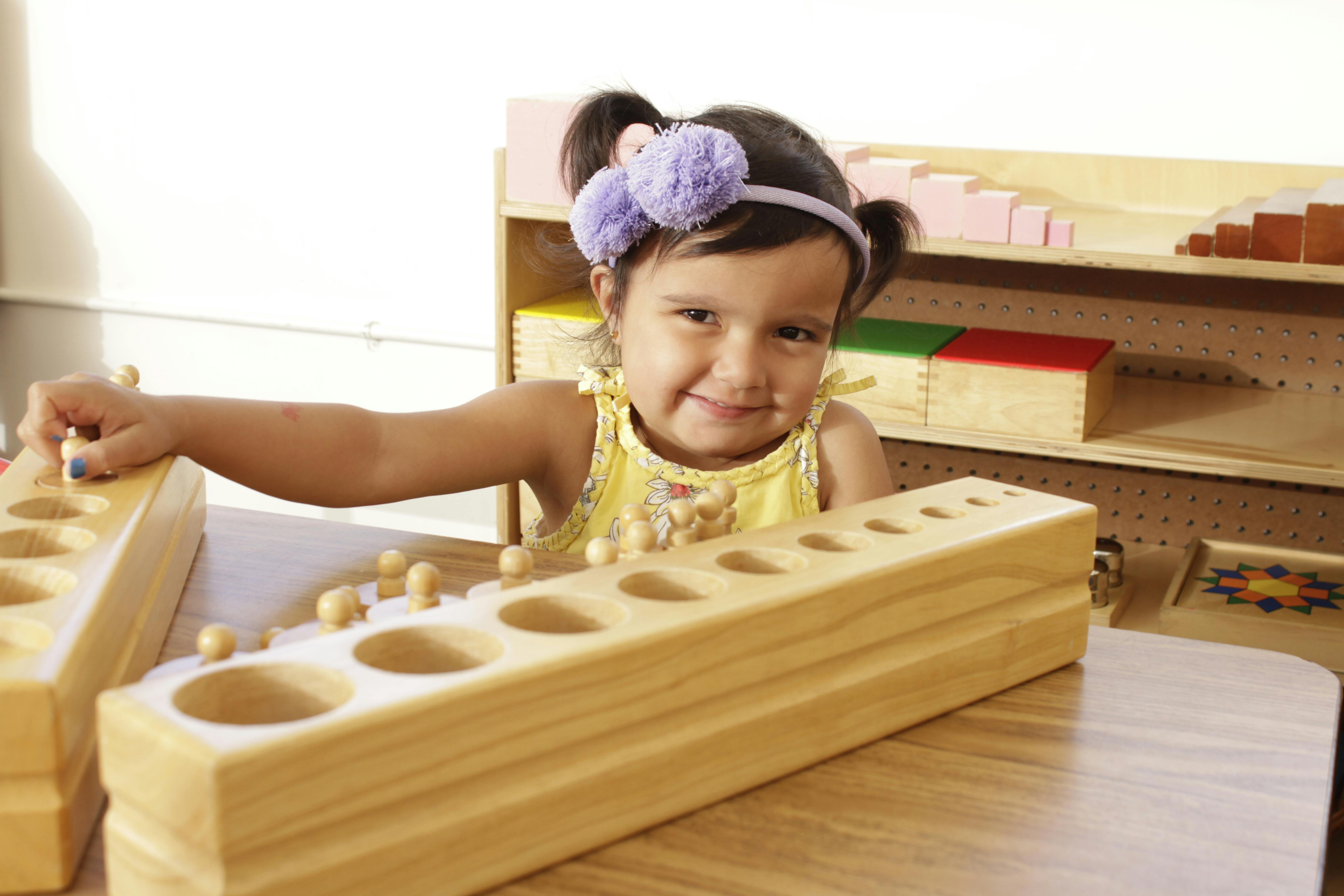 Child playing with wooden Montessori cylinder blocks