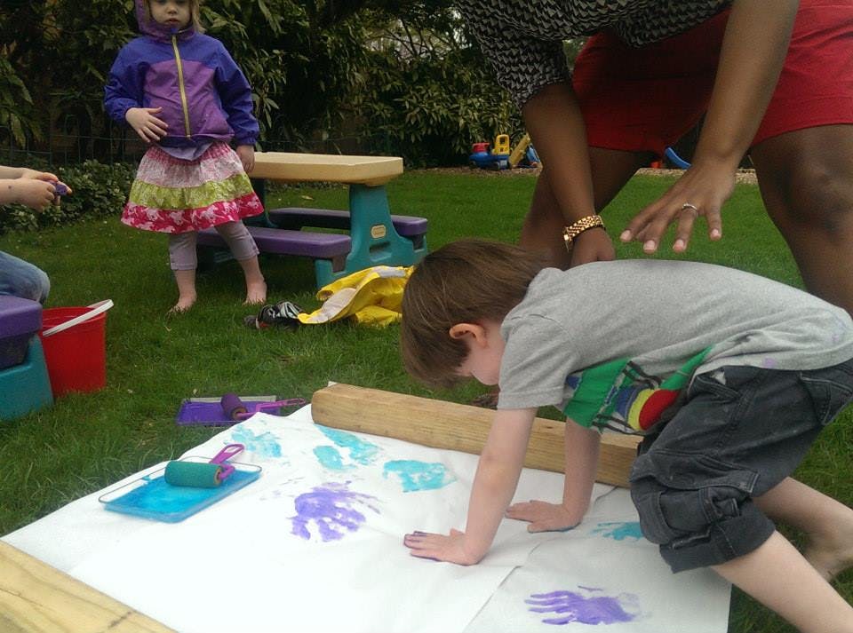 Child making handprints on paper outdoors