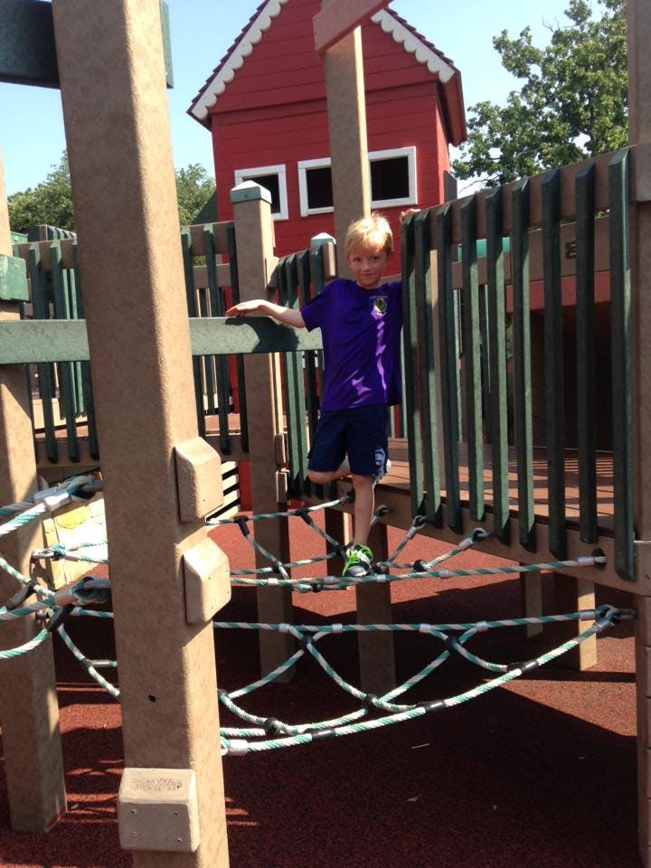 Child standing on a rope bridge on a playground