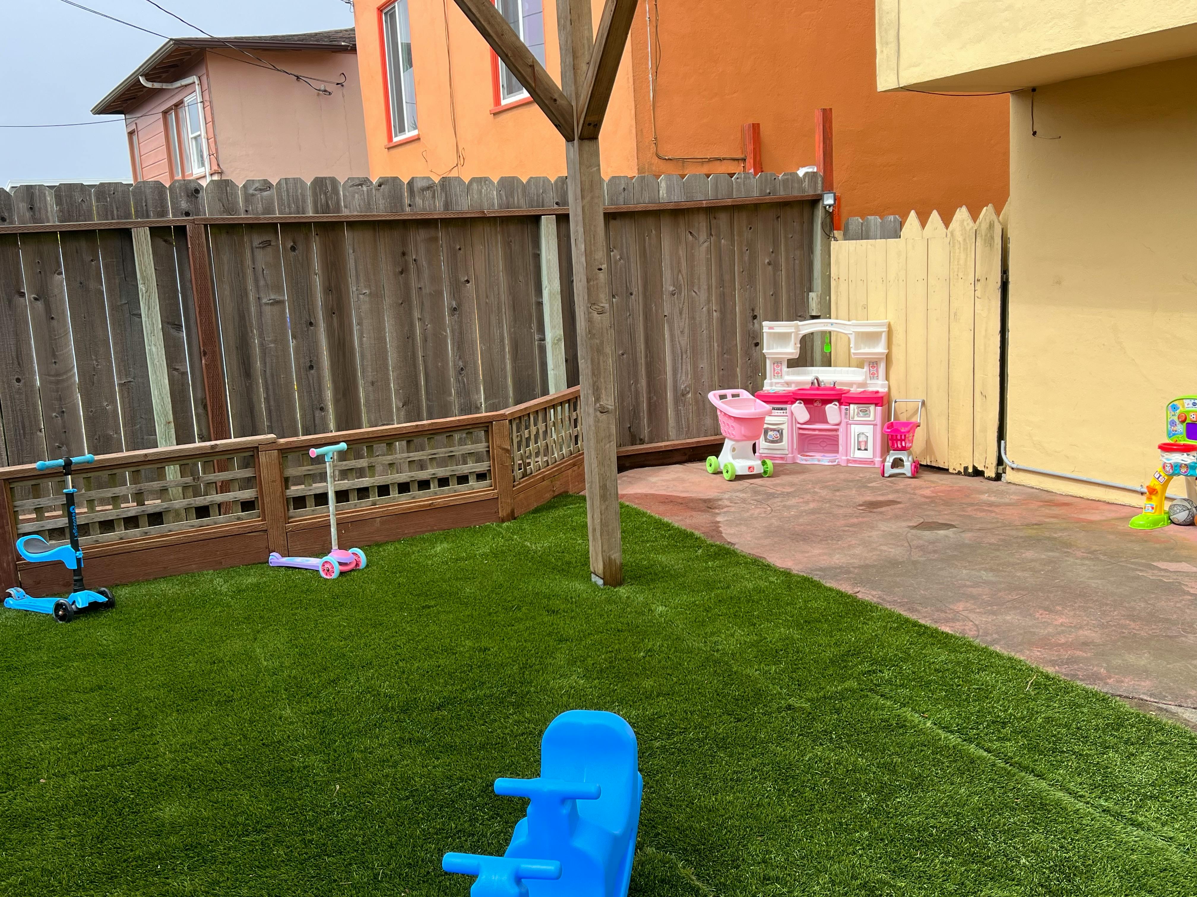 Backyard with artificial grass, play kitchen, and scooters