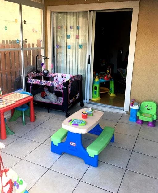 Play area with a crib, small picnic table, and other toys on a tiled patio