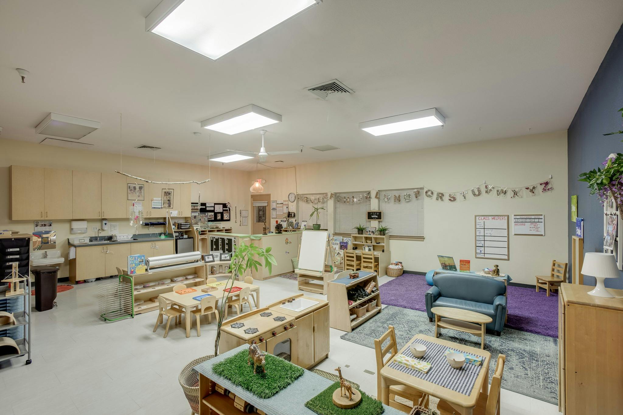 Classroom with small tables, chairs, and a blue couch