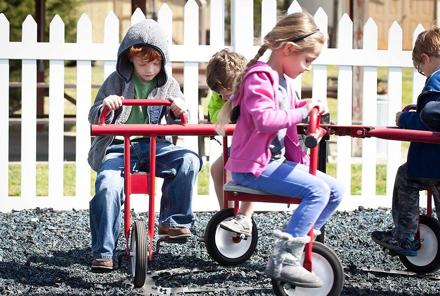 Children riding red tricycles on a playground