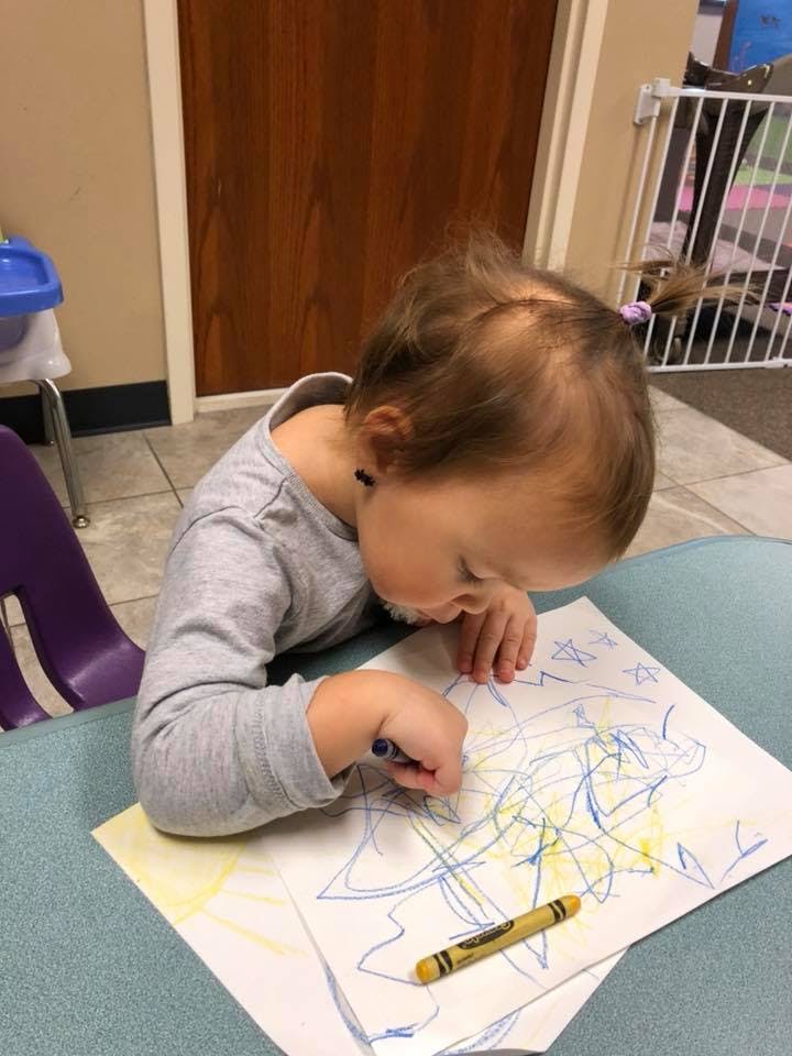 Child drawing on paper with crayons