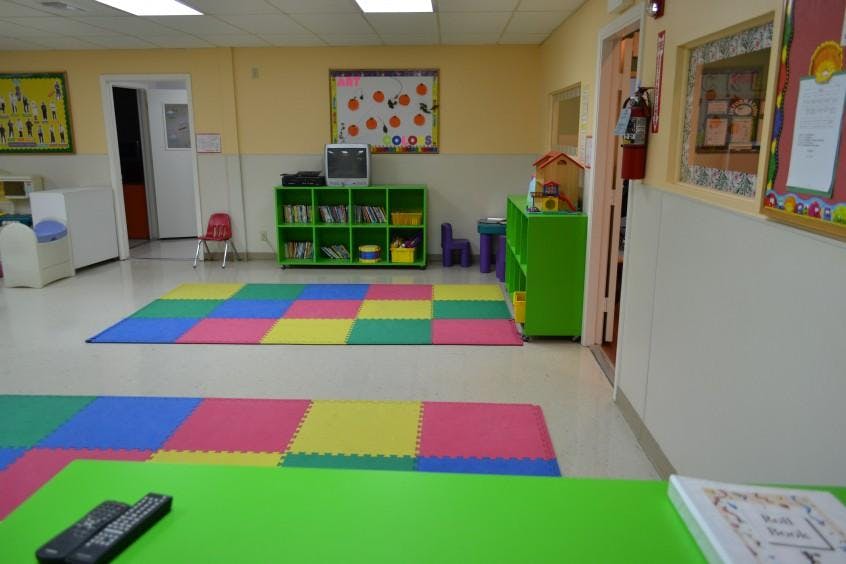 Empty classroom with colorful floor mats and green shelves