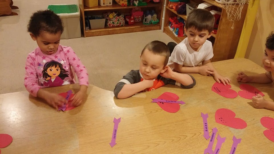 Children at a table with heart shapes and purple objects