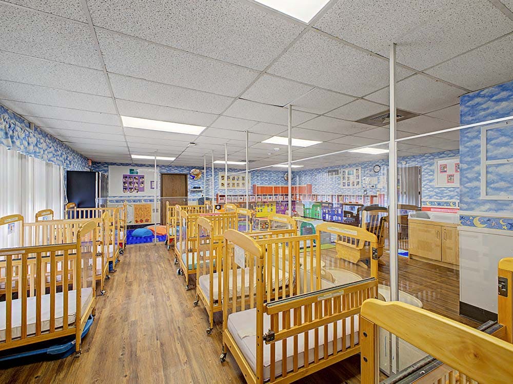 Rows of wooden cribs with mattresses in a brightly lit room
