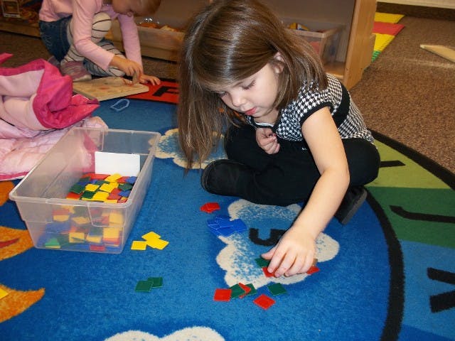 Child playing with colorful blocks on a blue rug